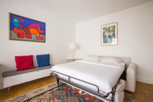 biała sypialnia z łóżkiem i kanapą w obiekcie Veeve - A Pop of Colour w Paryżu