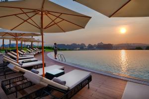 下龍灣的住宿－FLC Halong Bay Golf Club & Luxury Resort，水边的躺椅和遮阳伞