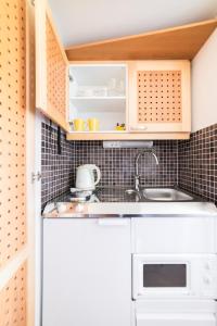 a small kitchen with white cabinets and a sink at Lossiranta Lodge in Savonlinna