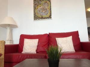 a red couch in a living room with a potted plant at Sea You Apartamentos Valencia Port Saplaya in Port Saplaya