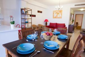 a dining room table with blue plates and wine glasses at Sea You Apartamentos Valencia Port Saplaya in Port Saplaya