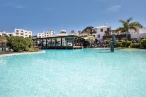 a large pool of blue water in front of buildings at Hotel LIVVO Volcán Lanzarote in Playa Blanca
