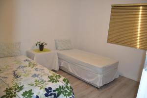 a room with two beds and a table and a window at Heloise Home Stay in Oudtshoorn