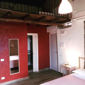 a room with red walls and a bed and a mirror at B&B Camerana in Messina