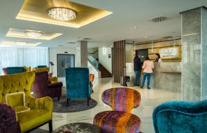 a lobby with colorful furniture and people standing in the lobby at Hotel Golden Lake Resort in Balatonfüred +58 photos