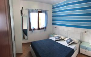 een slaapkamer met een bed met een blauwe en witte streepmuur bij IL MARE DI OLBIA Holiday Apartment in Olbia