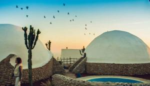 a woman standing in front of two domes with birds in the sky at DAV MAHAL Eco lodge in Sidi Kaouki