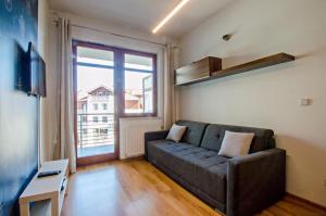 a living room with a couch and a large window at Grand Apartments - Neptun Park Maritime Apartment with balcony in Gdańsk