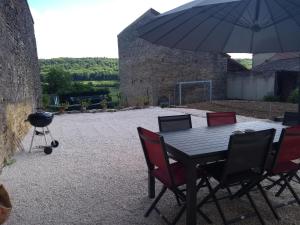 einen Tisch und Stühle mit Grill und Sonnenschirm in der Unterkunft Gite des Celliers in Alise-Sainte-Reine