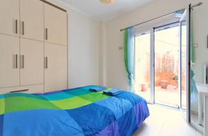 a bedroom with a colorful bed and a sliding glass door at Courtyard Apt - Central Athens in Athens