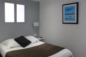 um quarto com uma cama e duas janelas em Appartement Vue Mer Au Jardin De La Comtesse em Saint-Quay-Portrieux
