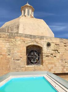 a building with a window and a tower with a cross at 6 in Birgu