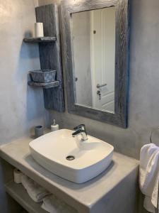 ein Badezimmer mit einem Waschbecken, einem Spiegel und Handtüchern in der Unterkunft Galini Apartments in Trapezaki