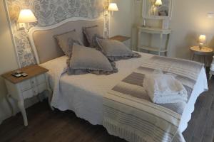 una camera da letto con letto bianco, cuscini e specchio di Romantic Home a Sirmione
