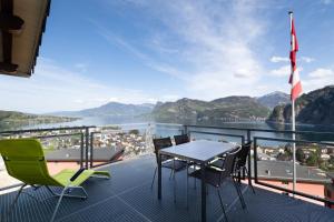 balcón con mesa, sillas y vistas al agua en Hotel Roggerli en Hergiswil