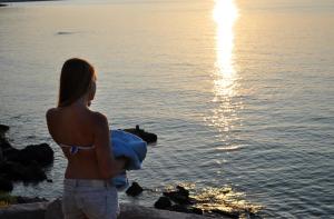 a woman holding a baby looking at the water at Hara's Studio in Perdika