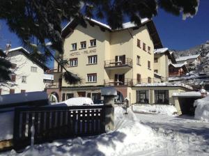 a large building with a fence in the snow at Hotel Milano in Folgaria