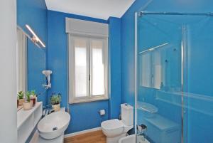 y baño azul con aseo y ducha. en Suite Manin en Treviso