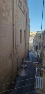an empty alley with a large brick building at 6 in Birgu