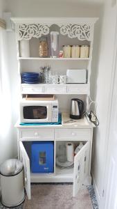 a kitchen with a white shelf with a microwave at Urban Log Cabin near zone 2 tube in London