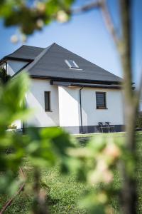 a white house with a black roof and some grass at Domek u Mai in Zator