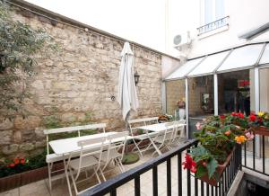 eine Terrasse mit Tischen, Sonnenschirm und Blumen in der Unterkunft Hôtel du Parc in Malakoff