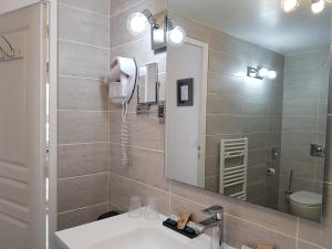 a bathroom with a sink and a mirror at Hôtel L'ideal le Mountbatten in Arromanches-les-Bains