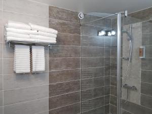 La salle de bains est pourvue d'une douche et de serviettes murales. dans l'établissement Hôtel L'ideal le Mountbatten, à Arromanches-les-Bains