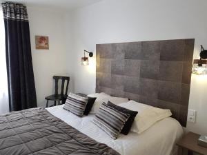 a bedroom with a bed with two pillows on it at Hôtel L'ideal le Mountbatten in Arromanches-les-Bains