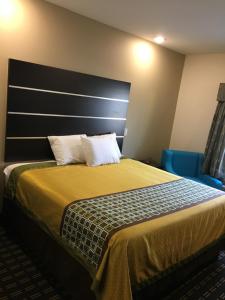 a hotel room with a bed and a blue chair at Americas Best Value lnn- Plaquemine in Plaquemine
