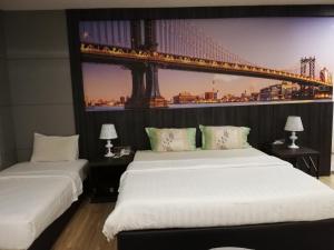 two beds in a room with a bridge on the wall at Ease Hotel in Kota Kinabalu