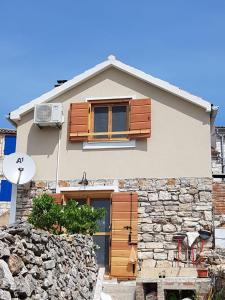 a house with wooden doors and a stone wall at Villa Duboka, Otok Vis in Komiža
