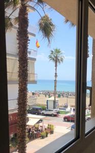 een raam met palmbomen en uitzicht op het strand bij EVE Malagueta in Málaga