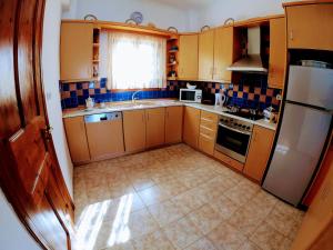 a small kitchen with wooden cabinets and a refrigerator at Korali in Symi