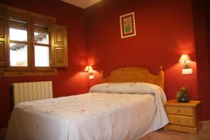 a bedroom with a bed with red walls and a window at Apartamentos Cañones de Guara y Formiga in Panzano