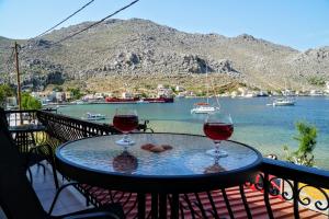 two glasses of wine sitting on a table on a balcony at Korali in Symi