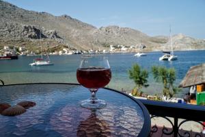 a glass of wine sitting on a table next to the water at Korali in Symi
