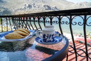 a table with a cup of coffee and bread on a balcony at Korali in Symi