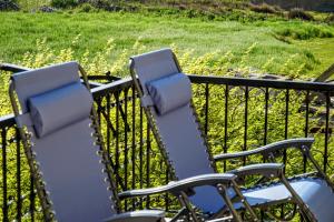 two chairs on a balcony with a field of grass at Korali in Symi