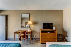 a hotel room with a desk and a table with a television at Beachside Motel - Amelia Island in Amelia Island