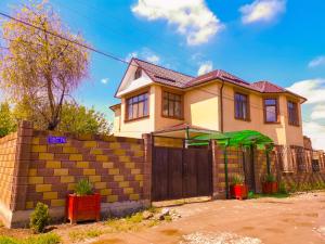 ein gelbes Haus mit einem Zaun und einem Tor in der Unterkunft Kurak Homestay in Bischkek