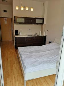 a bedroom with a white bed and a kitchen at Apartament Trzy Korony 1 in Świnoujście