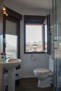 a bathroom with a toilet and a sink and two windows at Pension Reconquista in Cangas de Onís