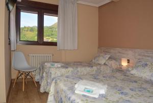 a hotel room with two beds and a window at Pension Reconquista in Cangas de Onís