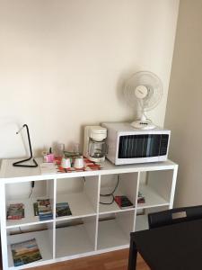 a white shelf with a microwave and a fan at Maison Chez Laurent in Baie-Saint-Paul