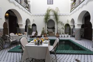 dziedziniec ze stołami i krzesłami oraz basenem w obiekcie Riad Maison Belbaraka w Marakeszu