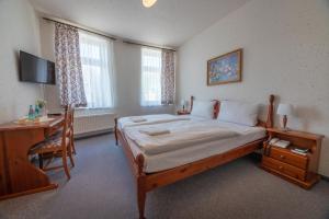 a bedroom with a large bed with a desk and a chair at Haus Schlematal Hotel und Restaurant in Bad Schlema