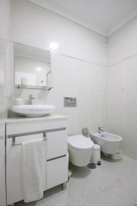 uma casa de banho branca com um lavatório e um WC em Salinas Beach House - T3 Apartment - Costa Nova em Costa Nova