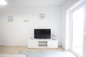 uma sala de estar branca com uma televisão numa parede branca em Salinas Beach House - T3 Apartment - Costa Nova em Costa Nova