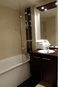 a bathroom with a sink and a mirror and a tub at Lagrange Apart’Hotel Paris-Boulogne in Boulogne-Billancourt
